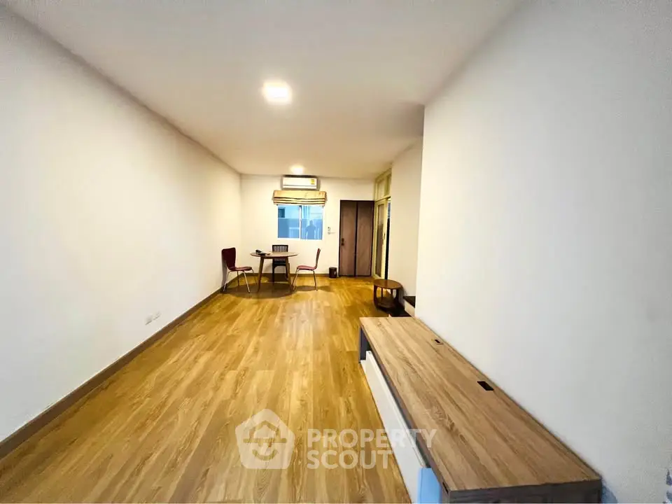 Spacious living room with wooden flooring and minimalist furniture in modern apartment.