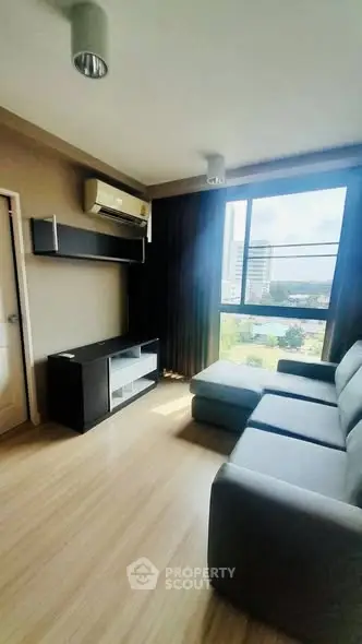 Modern living room with large window and sleek furniture in a high-rise apartment.
