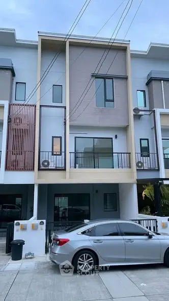Modern three-story townhouse with sleek design and spacious balcony in urban setting.