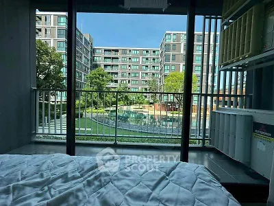 Modern apartment with pool view from bedroom, featuring large windows and lush greenery.