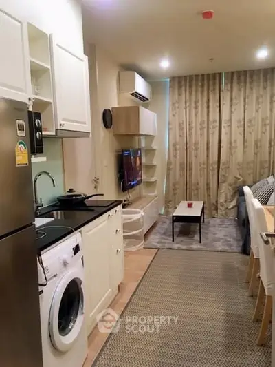 Modern compact living room with kitchen featuring washing machine and cozy decor.