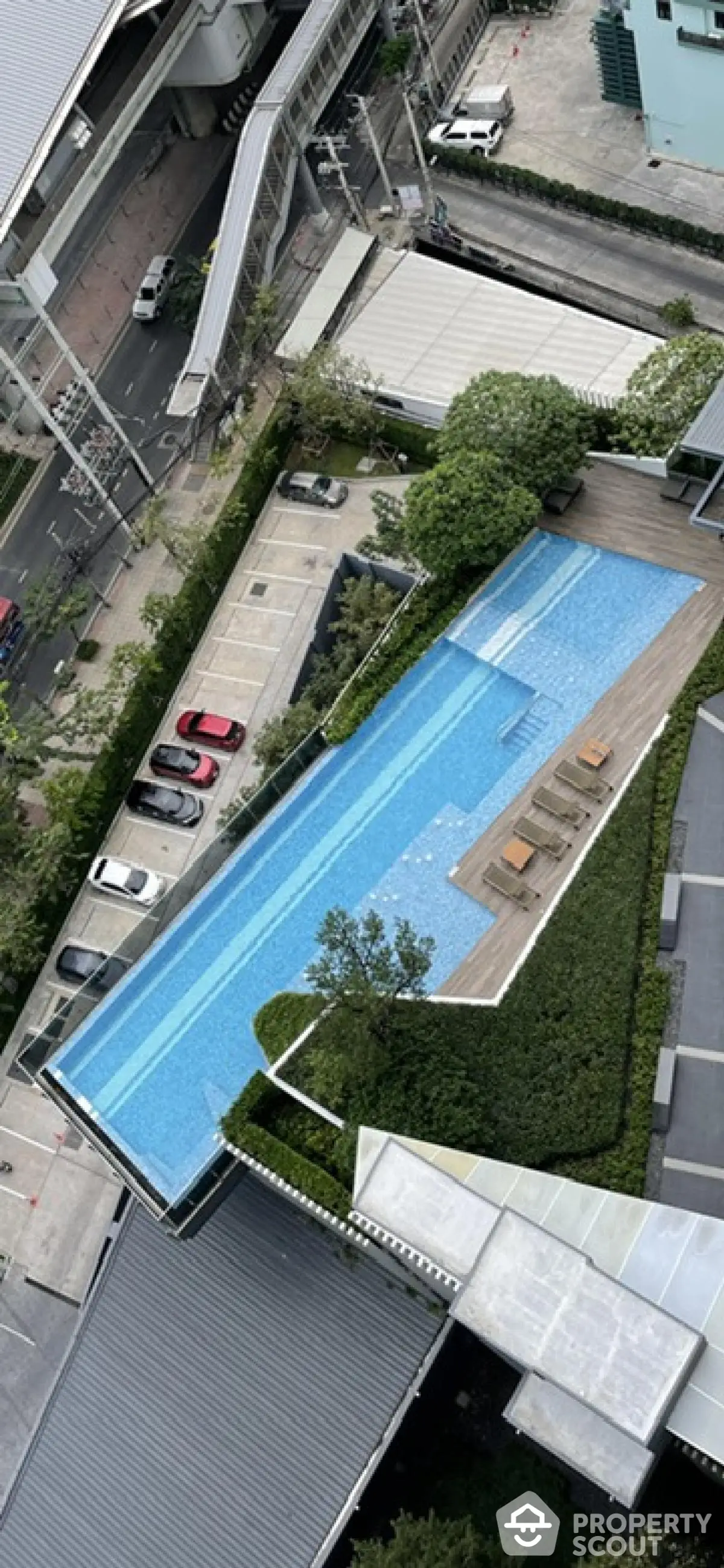 Stunning aerial view of modern rooftop pool with lush greenery and cityscape backdrop