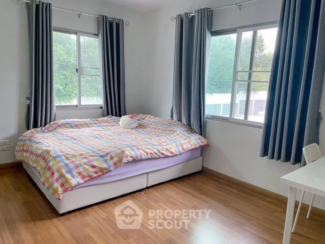 Bright bedroom with large windows and cozy bed, featuring wooden flooring and modern curtains.