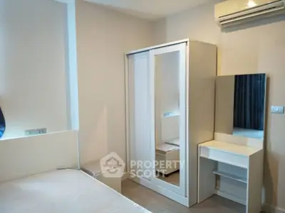 Modern bedroom with sleek white furniture and air conditioning unit, perfect for comfortable living.