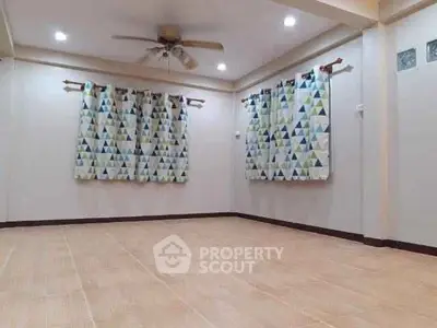 Spacious empty room with ceiling fan and patterned curtains, ready for customization.