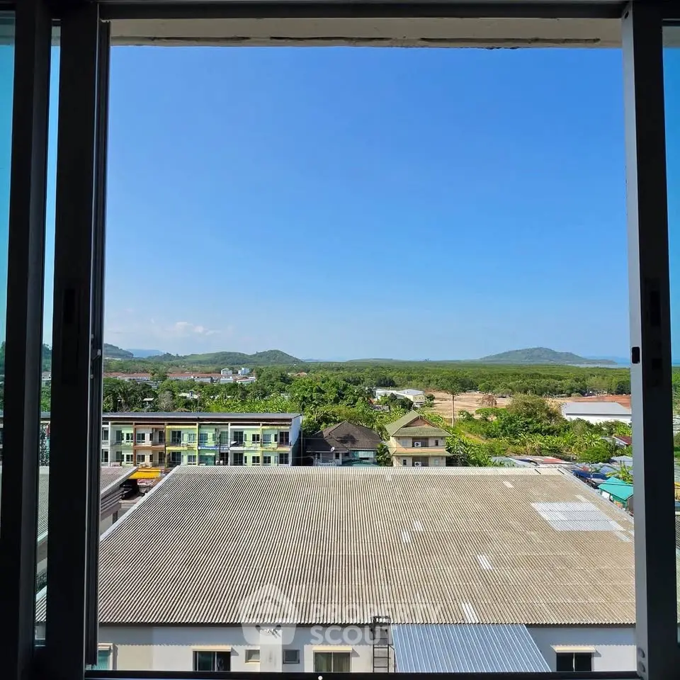 Stunning view from a high-rise window overlooking lush greenery and distant hills.