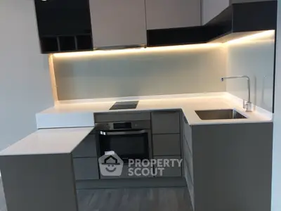 Modern kitchen with sleek cabinetry and built-in oven in a contemporary apartment.