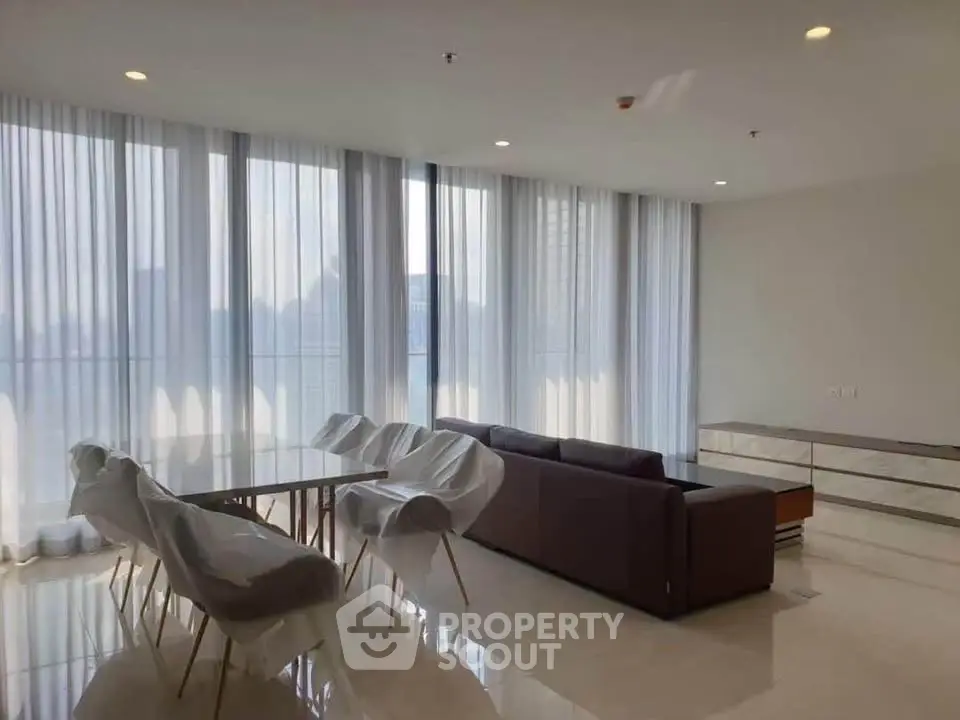 Spacious modern living room with elegant dining area and floor-to-ceiling windows.