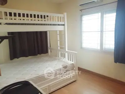 Cozy bedroom with bunk bed and natural light from window, perfect for small families or shared living.
