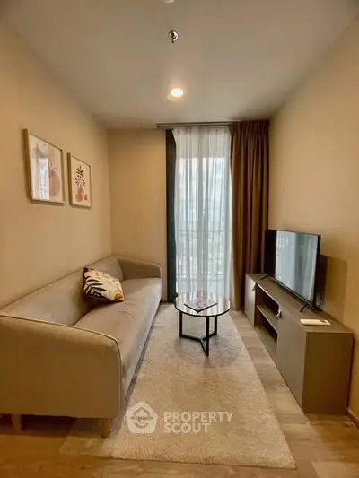 Cozy living room with modern sofa, TV, and natural light through large window.