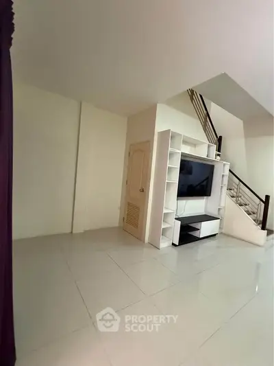 Spacious living room with modern TV unit and sleek staircase