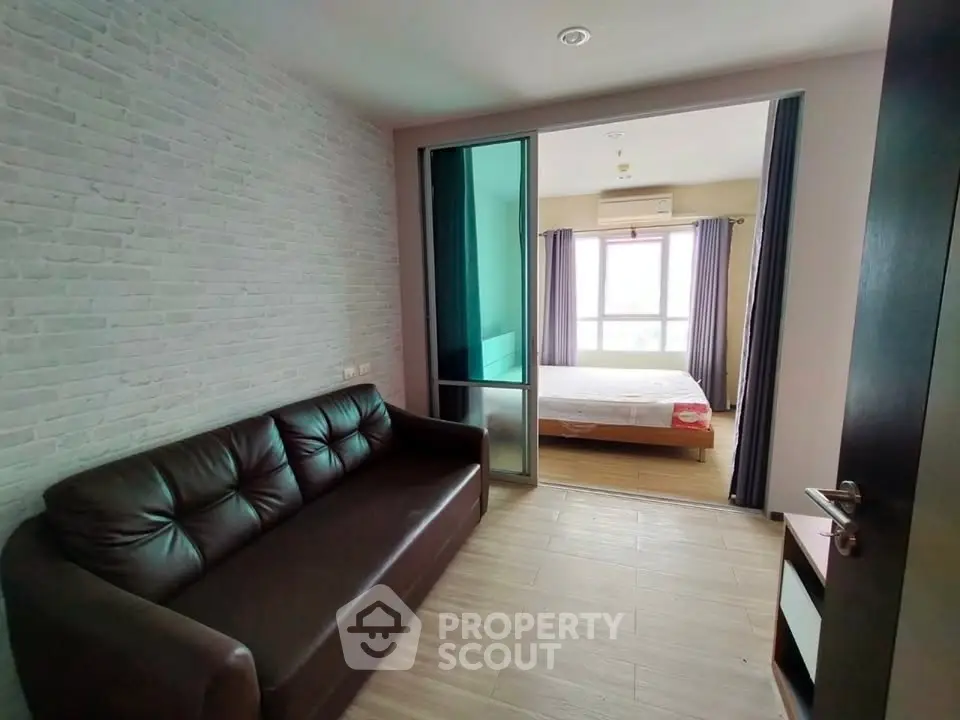 Modern apartment with cozy living room and bright bedroom separated by sliding glass door.