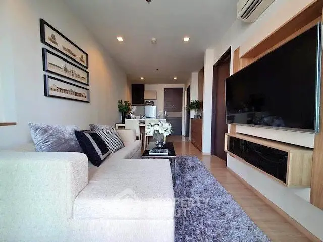 Modern living room with stylish decor and large wall-mounted TV in a cozy apartment.