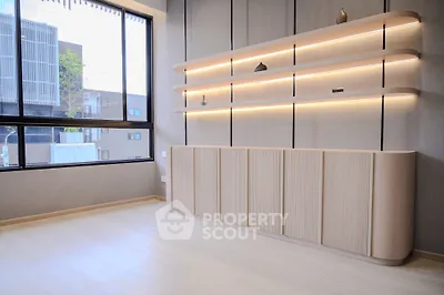 Modern minimalist living room with sleek built-in shelves and large window view.