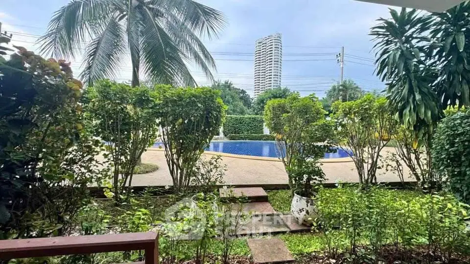 Lush garden view with pool and high-rise building in the background