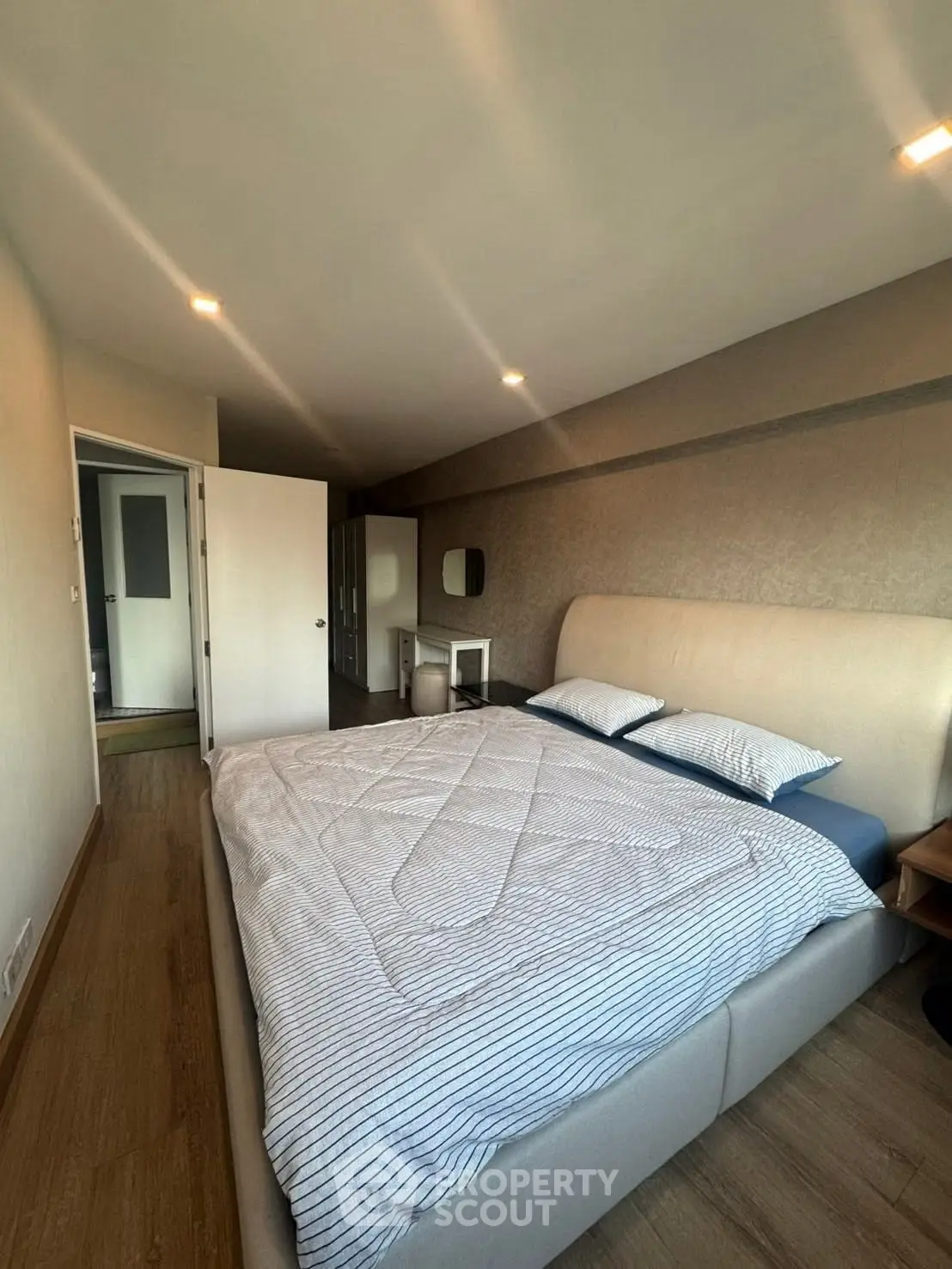 Spacious bedroom with modern decor and ample natural light, featuring a comfortable bed and stylish furnishings.