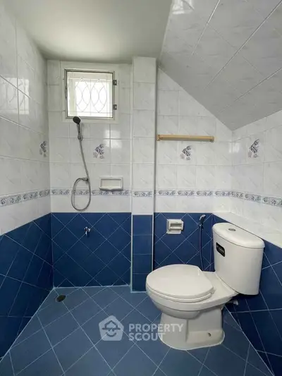 Compact bathroom with blue and white tiles and modern fixtures.