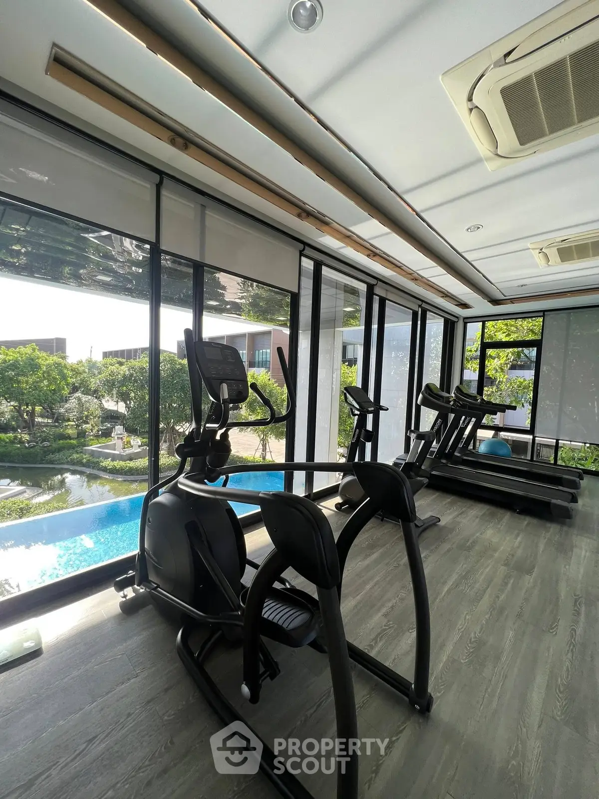 Modern gym with pool view and exercise equipment in luxury real estate property.
