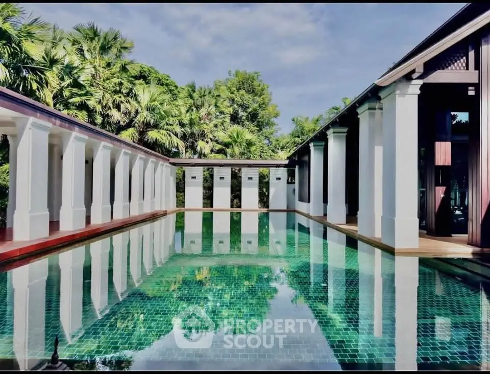 Luxurious villa with stunning pool surrounded by lush greenery and elegant architecture.