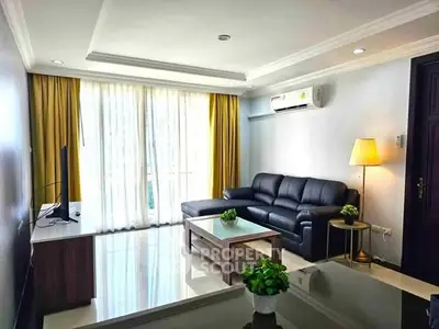 Modern living room with sleek black sofa and large window for natural light.