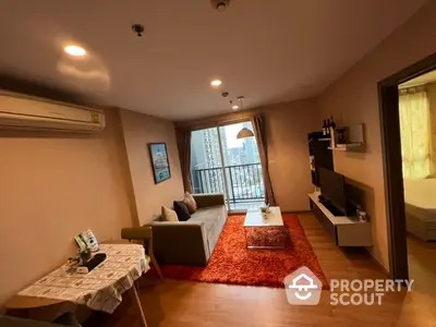 Cozy and inviting living space with warm wooden flooring, comfortable sofa, and a charming balcony with a view, perfect for urban living.