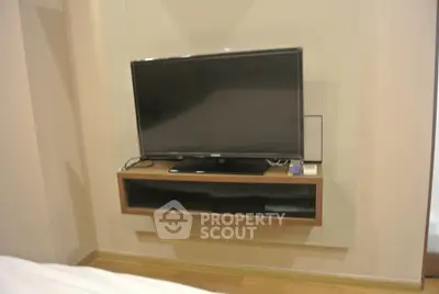 Modern bedroom with wall-mounted TV and sleek wooden shelf