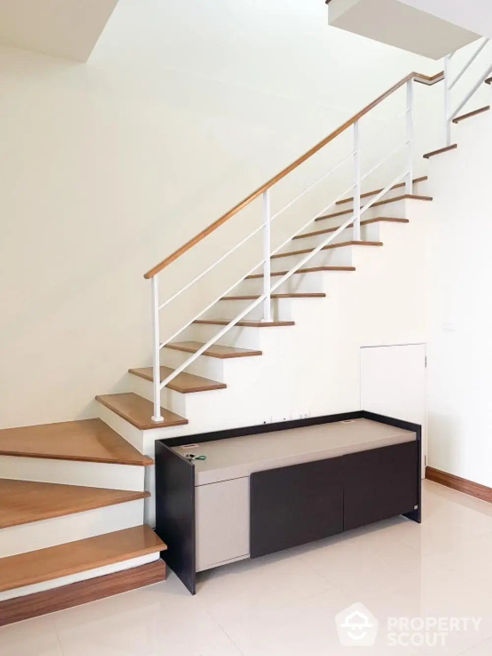 Elegant staircase with wooden steps and modern metal railings in a bright, spacious home interior, showcasing sophisticated design and architecture.