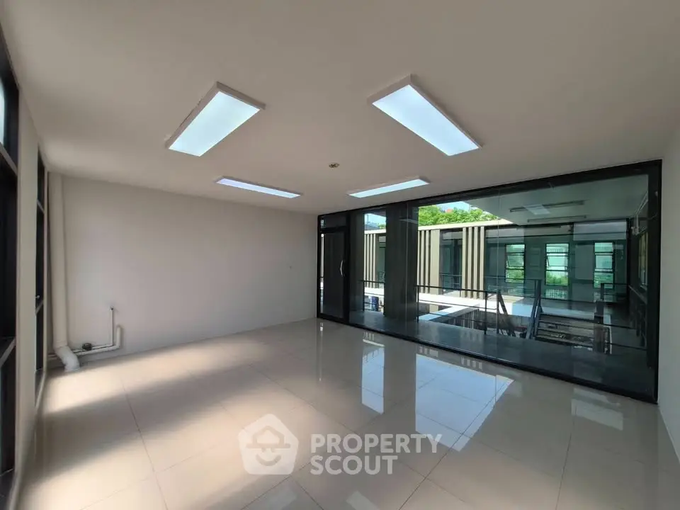 Spacious modern living room with large windows and sleek tile flooring.