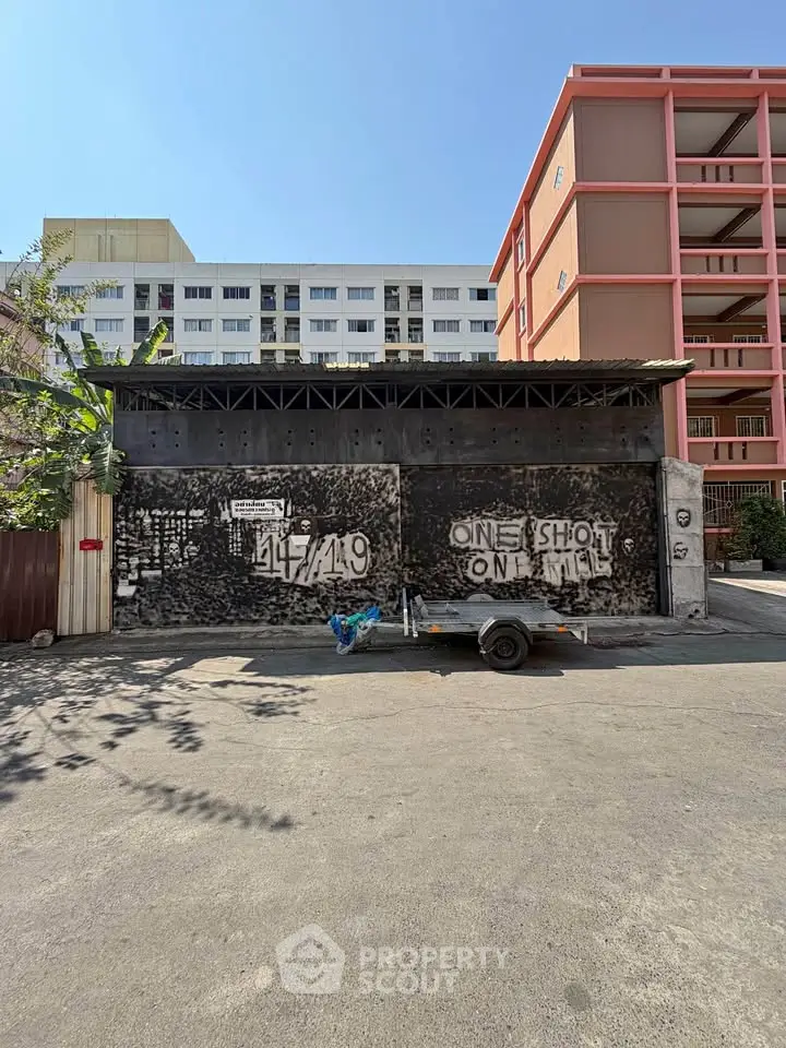 Urban street view with graffiti wall and residential buildings in the background, showcasing city life.