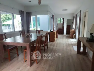 Spacious dining area with wooden furniture and large windows in a modern home.