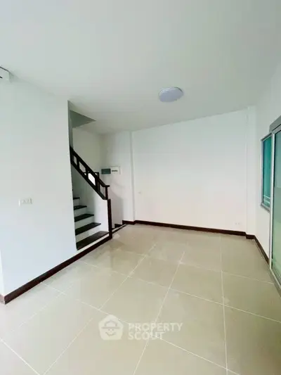 Spacious modern living room with staircase and large windows in a contemporary home.