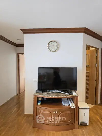 Cozy living room with wooden flooring and TV stand, perfect for relaxation.