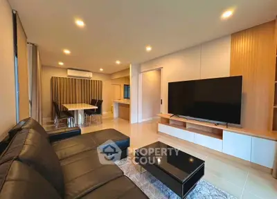 Modern living room with sleek black leather sofa and large flat-screen TV
