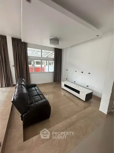 Spacious living room with modern leather sofa and large windows