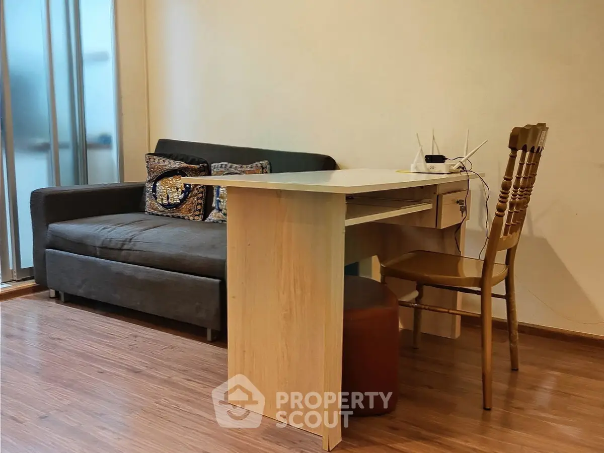 Cozy living room with modern sofa and wooden desk, perfect for a home office setup.