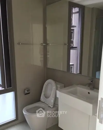 Modern bathroom with sleek fixtures and large mirror in a contemporary apartment.