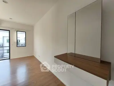 Spacious modern living room with sleek wooden flooring and large windows for natural light.