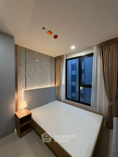 Modern bedroom with elegant lighting and large window in a stylish apartment.