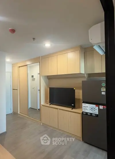 Modern apartment interior with sleek wooden cabinetry and a flat-screen TV, showcasing contemporary living space.