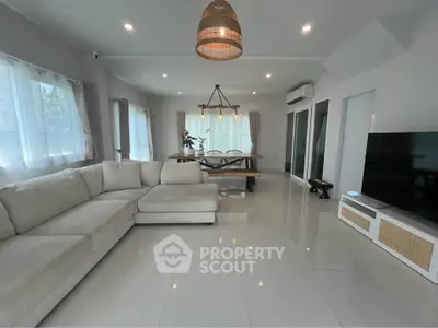 Spacious modern living room with large sectional sofa and dining area, perfect for family gatherings.