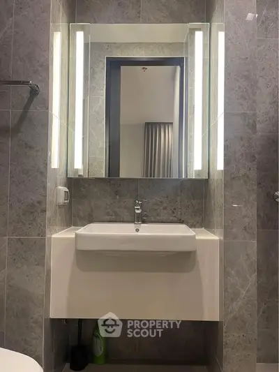 Modern bathroom with sleek sink and illuminated mirror in stylish apartment.