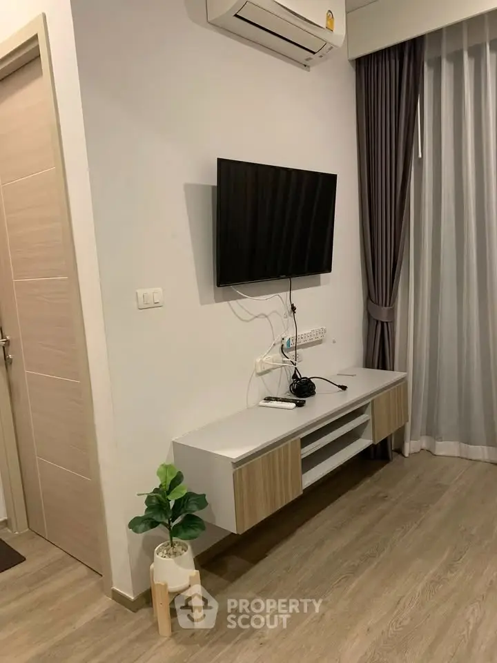 Modern living room with wall-mounted TV and stylish furniture in a cozy apartment.