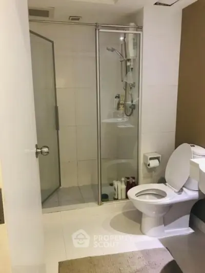 Modern bathroom with glass shower and white fixtures in real estate property.