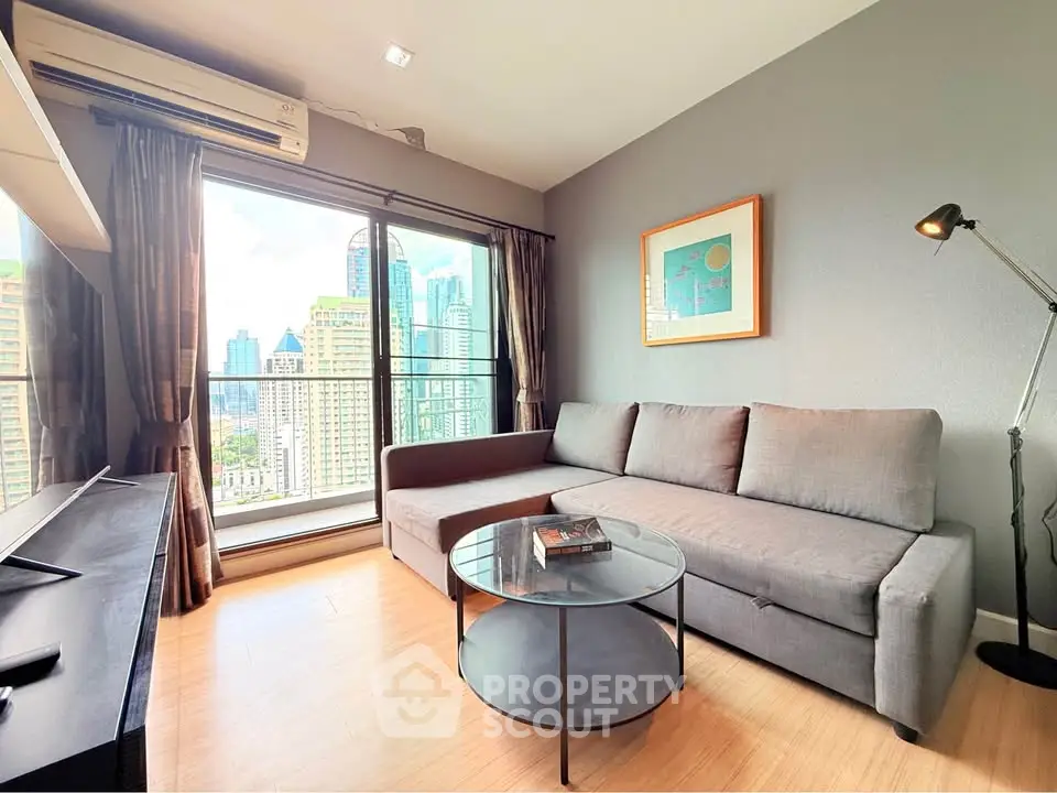 Modern living room with city view, featuring a sleek gray sofa and stylish decor.