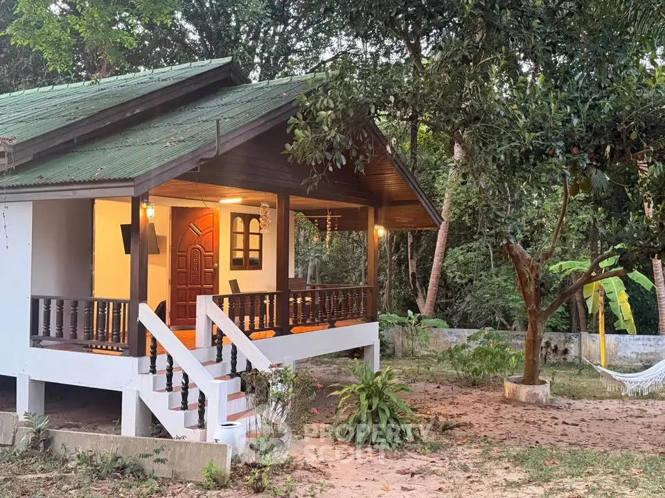 Charming elevated cottage with inviting porch nestled in lush greenery, perfect for serene living.