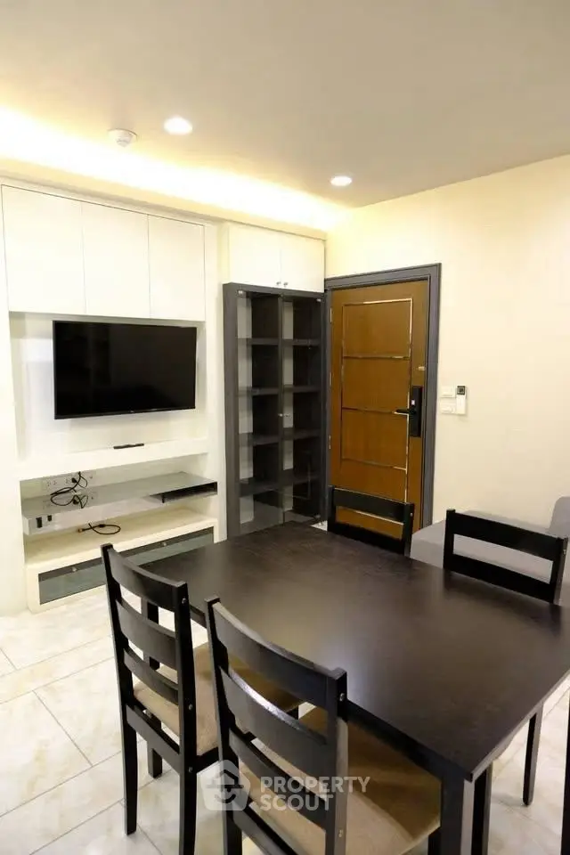 Modern dining area with sleek black table and built-in TV unit