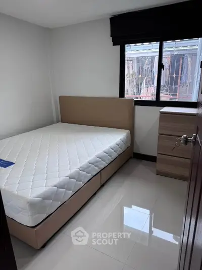 Cozy bedroom with modern furnishings and large window offering natural light.