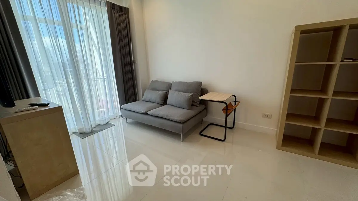 Modern living room with sleek sofa and natural light from large window.