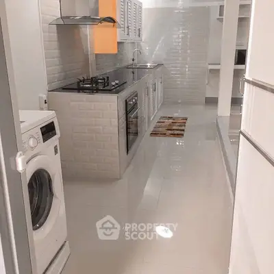 Modern kitchen with sleek appliances and washing machine in open layout
