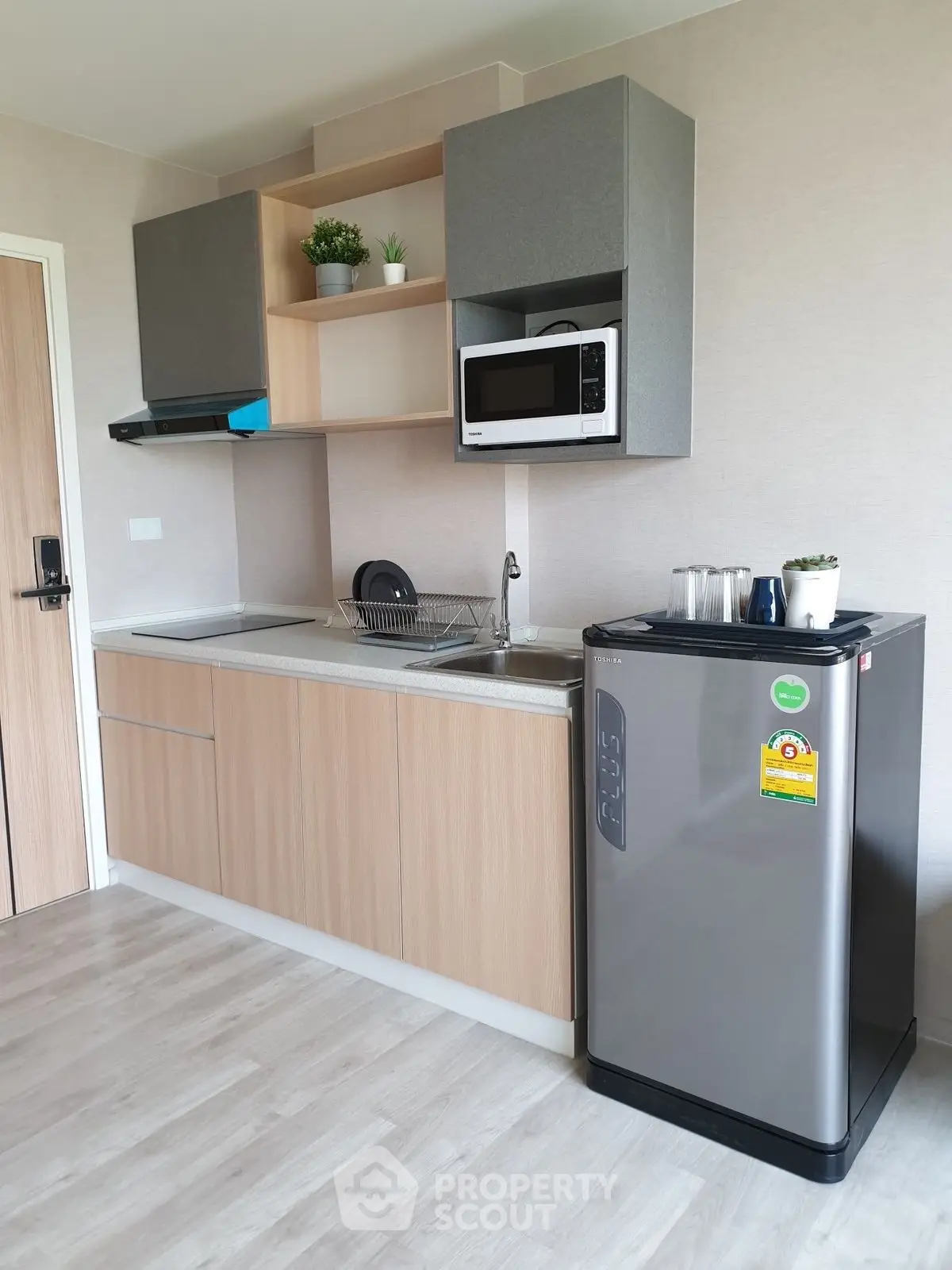 Modern kitchen with sleek cabinetry, compact fridge, and microwave in a stylish apartment.